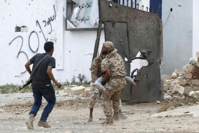 Fighters loyal to Libya's Government of National Accord carry a wounded man, as clashes rage south of the capital Tripoli