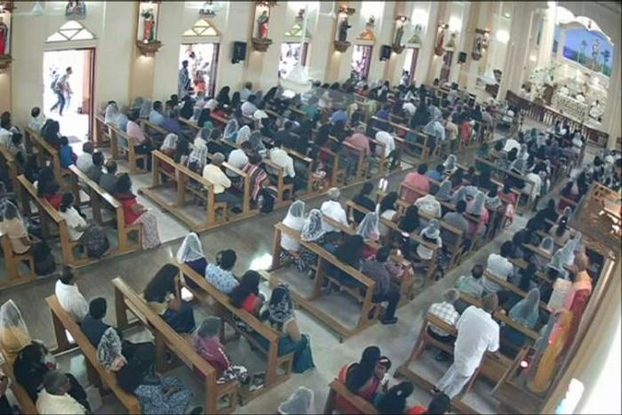 The suspected bomber walks past a door (L) with a backpack on, before entering St. Sebastian's Church in Negombo
