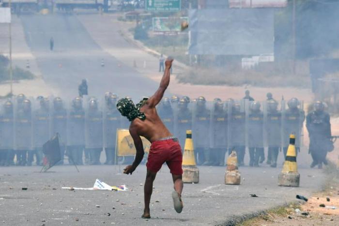 A demonstrator throws stones at Venezuelan National Guard troops on the border with Brazil at Pacaraima, Roraima state, on February 24, 2019