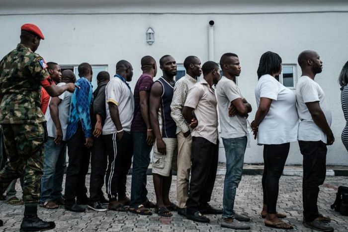 Suspects who were arrested by Nigerian Army personnel on election day in connection with various alleged electoral offenses, including stealing a carton of presidential ballot papers, stand in line to be handed over to police in Port Harcourt