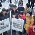 People in Pyongyang gather to read a copy of the Rodong Sinmun newspaper showing coverage of North Korea's leader Kim Jong Un arriving in Vietnam ahead of a Hanoi summit with US President Donald Trump