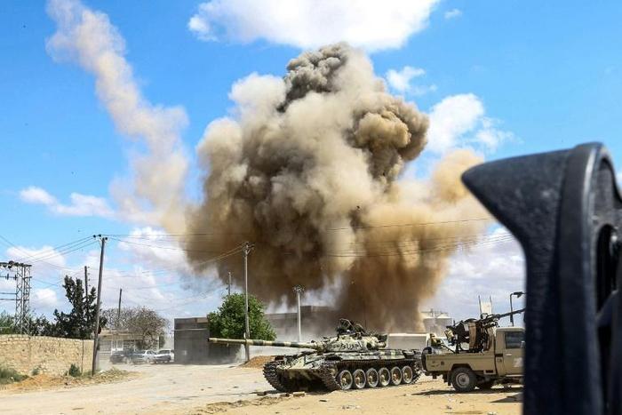 Smoke rising from an air strike behind vehicles belonging to forces loyal to Libya's unity government, in the suburb of Wadi Rabie south of the capital Tripoli on Friday