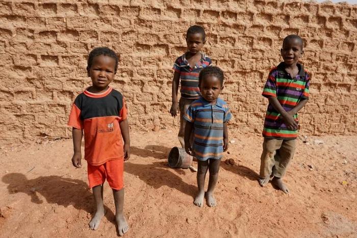 A group of children pose for photographs on a street in Agadez, northern Niger on April 1, 2017