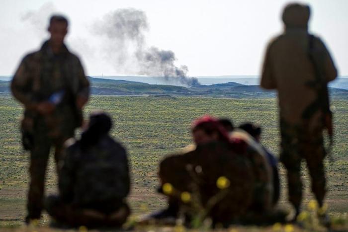 Smoke billows as fighters with the US-backed Syrian Democratic Forces keep watch in the Baghouz area in eastern Syria on February 12, 2019 during an operation to expel hundreds of Islamic State group jihadists from the region