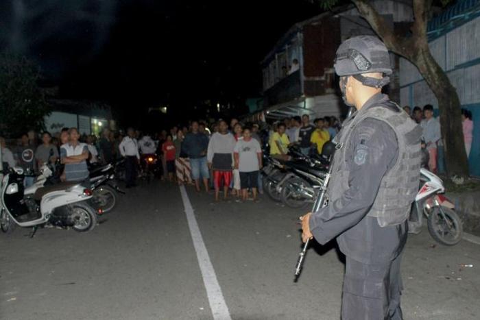 Officers stand guard after the explosion at the home of a suspected militant on Sumatra island