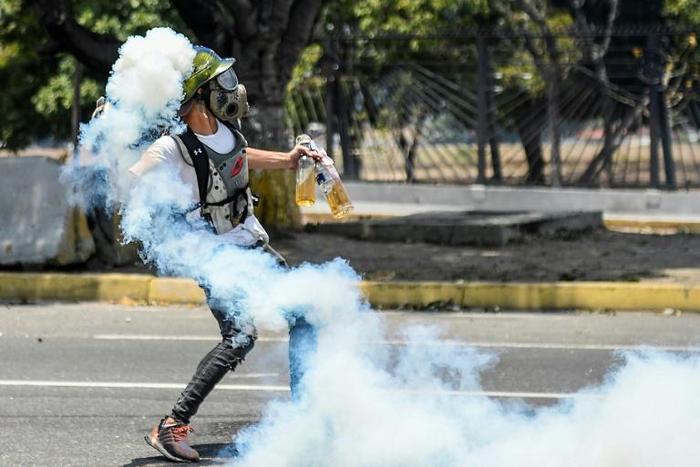 An anti-government protester throws Molotov cocktails during clashes with security forces near the La Carlota military base in Caracas