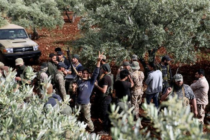 Syrian rebels gather in a field in the northern countryside of Hama province during clashes with regime forces