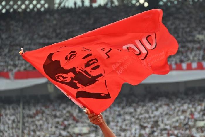 A supporter of incumbent Indonesian president Joko Widodo waves a flag bearing his portrait at an election rally in Jakarta