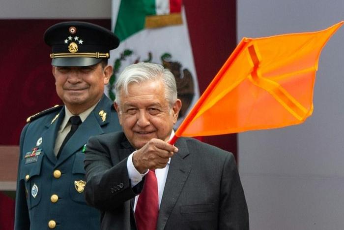 Mexican President Andres Manuel Lopez Obrador waves an orange flag as he declares work officially under way to turn the Santa Lucia military air base into a second airport for the sprawling capital