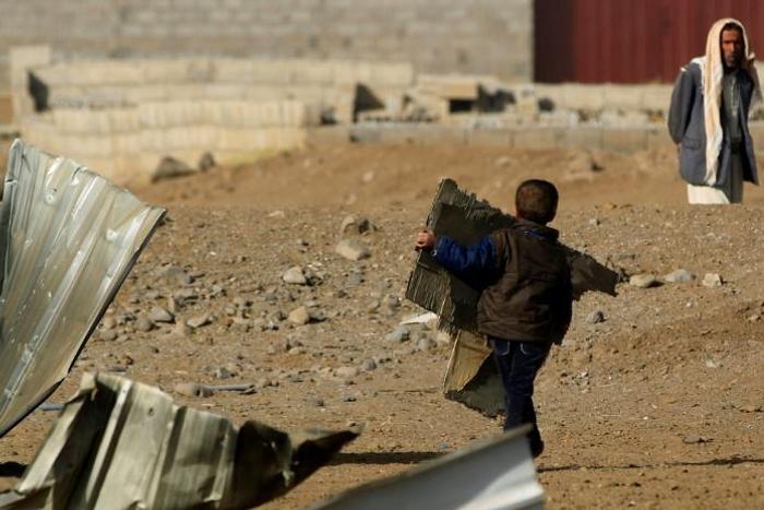 A child carries corrugated metal from the site of a reported airstrike by the Saudi-led coalition in the Yemeni capital Sanaa in January