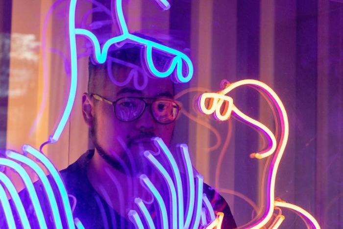 Chinese cartoonist Badiucao stands behind his artwork titled 'Light' in his studio in Melbourne