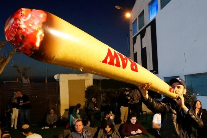 A supporter of Moshe Feiglin, leader of the far-right Zehout party, smokes a fake inflatable marijuana joint at a rally in the Israeli city of Tel Aviv on April 2, 2019