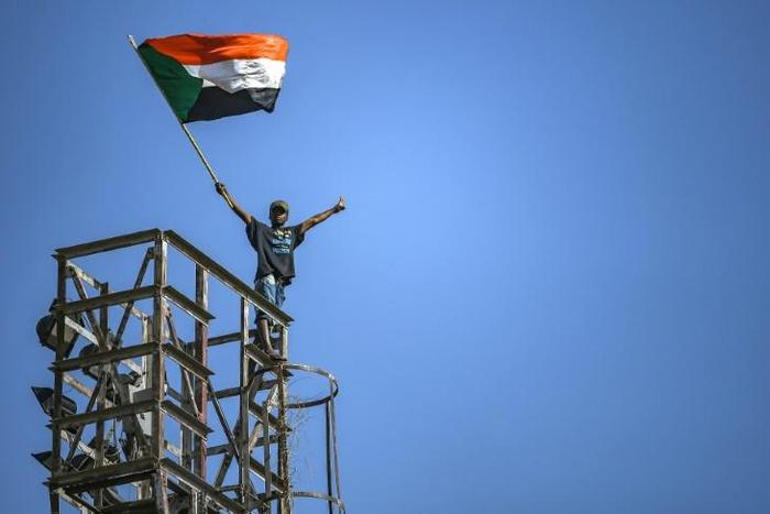 A protester waves a Sudanese flag on top of a tower during a sit-in outside the army headquarters in the capital Khartoum on April 30, 2019