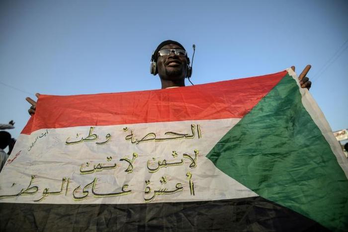 A protester flashes a Sudanese flag covered with patriotic slogans outside army headquarters in Khartoum