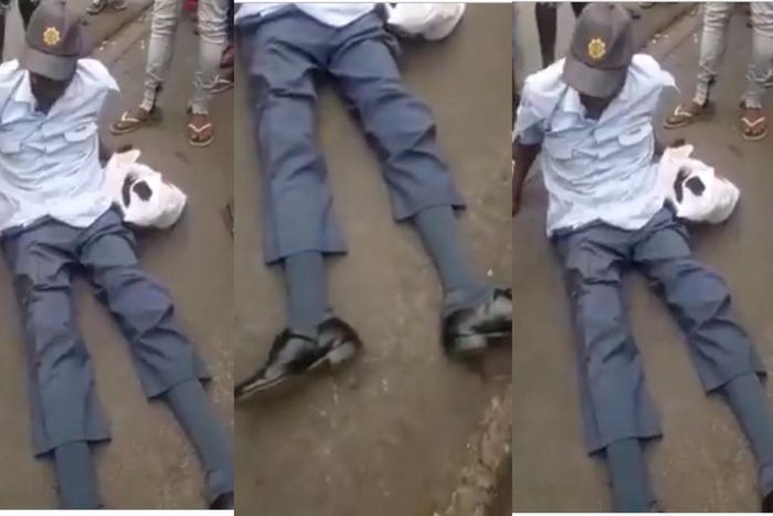 Crowd gather around drunk police officer as he is unable to rise up from the ground