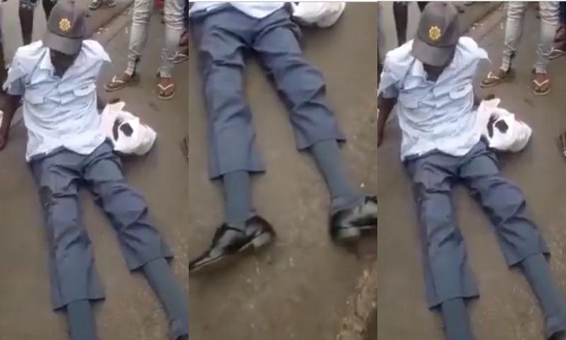 Crowd gather around drunk police officer as he is unable to rise up from the ground