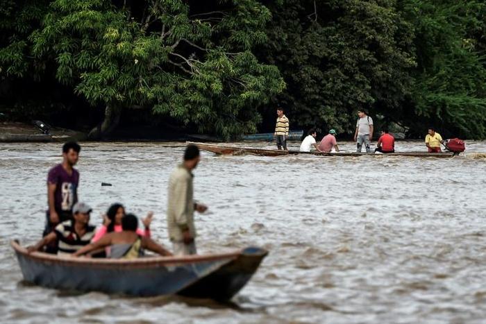 Venezuelans take boats from one muddy shore to the other to buy supplies from Colombia or journey onwards