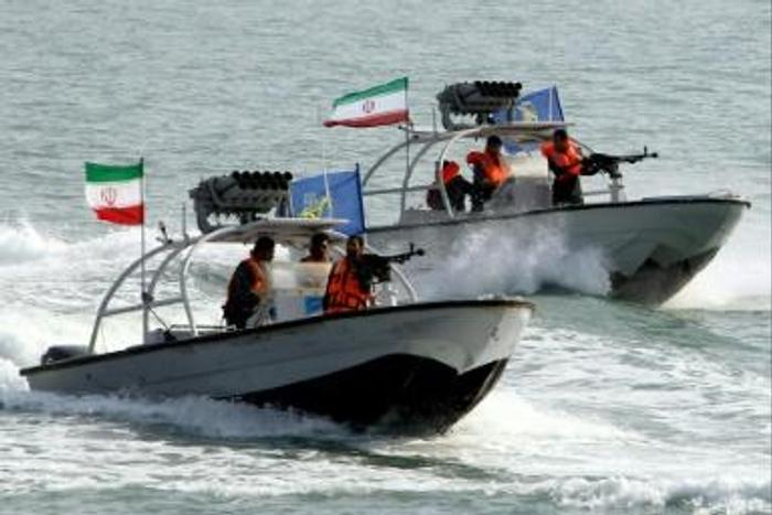 Iranian Revolutionary Guards drive speedboats at the port of Bandar Abbas in 2012 (L), and the amphibious assault ship USS Boxer is pictured during exercises in 2016