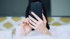 Portrait of woman using mobile phone while lying on bed