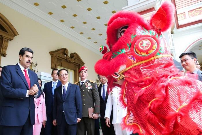 Venezuela's President Nicolas Maduro (L) and China's ambassador to Venezuela Li Baorong (C) watch a performance of a Chinese lion during a celebration marking 45 years of ties between the two countries, in June 2019
