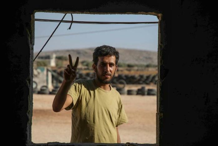 Mohammad al-Naeemi, a Syrian who returned from exile in Germany to join a rebel group, flashes a victory sign at a training camp near the Bab al-Hawa crossing between Iblib province and Turkey on July 18, 2019
