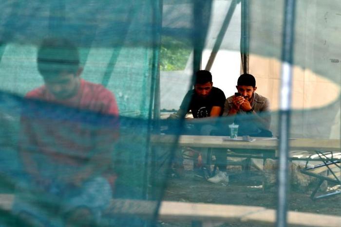 Migrants are pictured at a camp on the outskirts of the city of Bihac, in northern Bosnia near the Croatian border on July 2, 2019