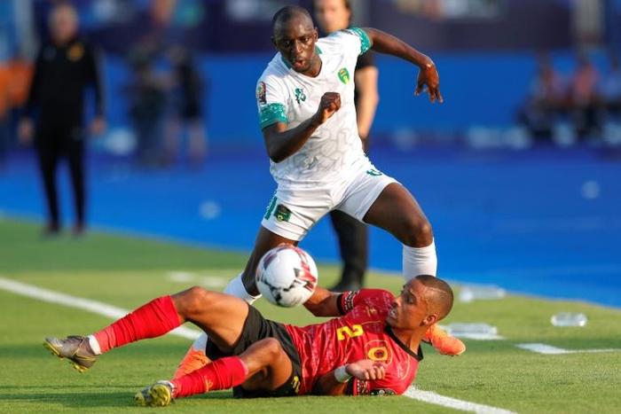Angola's defender Bruno Gaspar (bottom) vies for the ball with Mauritania's midfielder Khassa Camara during the 2019 Africa Cup of Nations (CAN) Group E football match between Mauritania and Angola at the Suez Stadium on June 29, 2019.