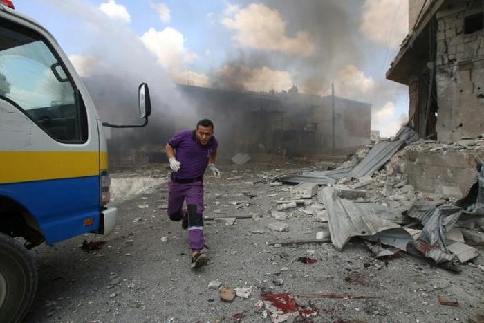 A rescuer from the Violet NGO runs during airstrikes by Syrian regime forces in Maar Shurin on the outskirts of Maarat al-Numan in northwest Syria on July 16, 2019