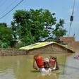A resident of Muzaffarpur carries gas canisters from his flooded home following heavy monsoon rains in the Indian state of Bihar