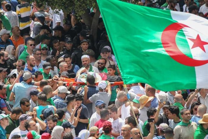 Algerians carry a protester on a stretcher at a weekly demonstration on July 5, 2019. Algerian police have opened an investigation after a video circulated online appeared to show protesters being beaten by security forces