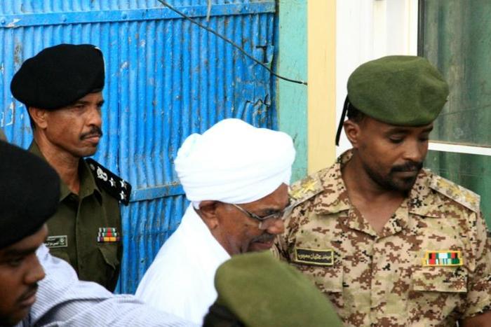 Ousted Sudanese leader Omar al-Bashir being escorted to hear charges of corruption against him in Khartoum: the Internatinal Criminal Court has called for him to face trial for genocide in Darfur