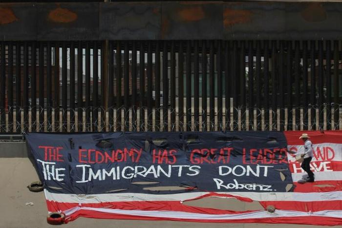 Mexican US resident Roberto Márquez, places a US flag on the border wall next to Rio Grande river in the border between El Paso, US, and Ciudad Juarez, Mexico, on June 9, 2019