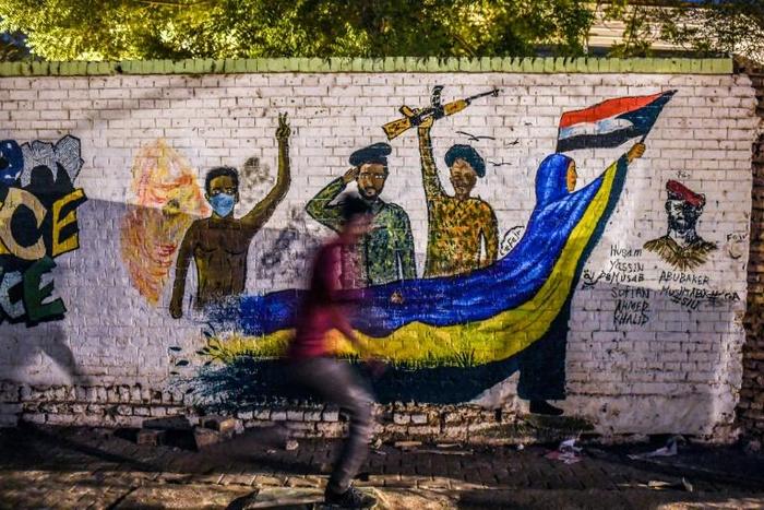 A Sudanese protester runs past a mural during a demonstration near army headquarters in the capital Khartoum back in April