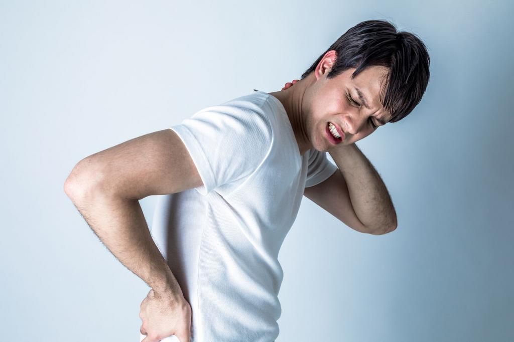 young man having horribly stiff shoulders
