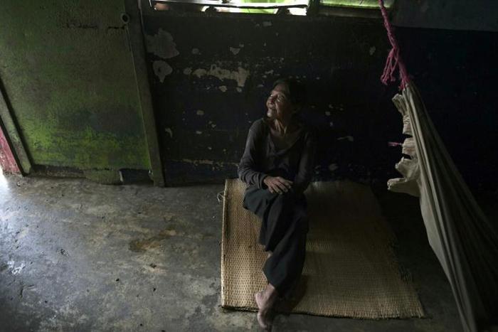A Yukpa woman suffering from fever due to malaria sits on the floor of her house on June 11, 2019