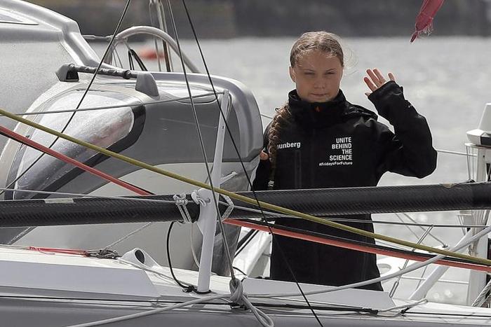 Swedish climate activist Greta Thunberg waves from aboard the Malizia II IMOCA class sailing yacht which is taking her to New York