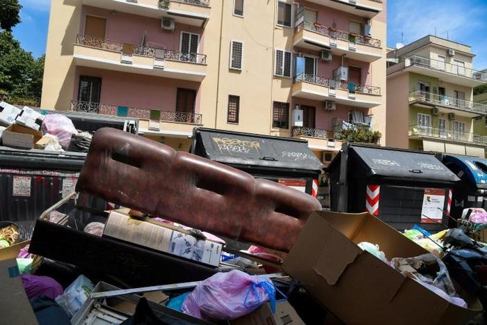 Crowds of summer tourists are forced to navigate overflowing bins in the stifling heat