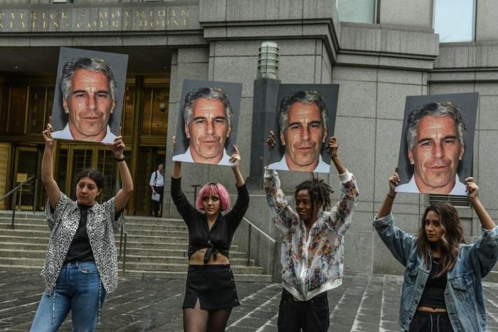 People hold signs of Jeffrey Epstein outside the federal courthouse in New York City on July 8, 2019, as Epstein was charged for sex trafficking minors