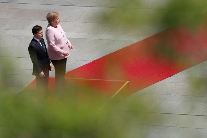 German Chancellor Angela Merkel visibly trembled for minutes while standing in the midday sun next to Ukrainian President Volodymyr Zelensky