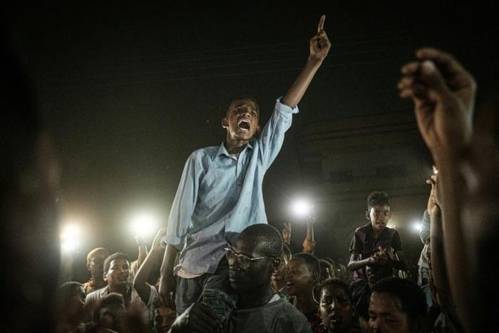 A man recites a revolutionary poem, as people gather in a southern district of Khartoum