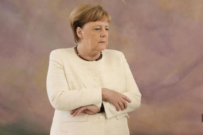 Merkel folded her arms visibly in a bid to stop the trembling. 