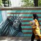 A woman walks past a mural on the wall of the former US embassy in the Iranian capital Tehran