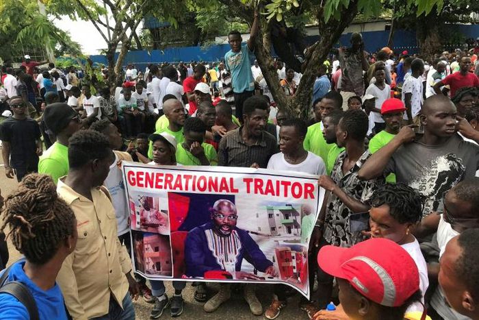 Demonstrators hold a poster portraying Liberian President George Weah as they gather outside the Liberian Mansion in Monrovia on June 7, 2019 during an anti-government march to protest inflation and corruption