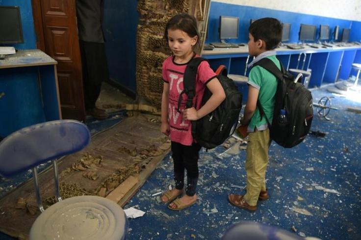 Afghan children stand in the debris at a school near the site of a Taliban car bomb attack in Kabul on July 2, 2019, a day after the deadly blast at the Defense Ministry's logistics centre that also damaged nearby buildings.At least six people were kil...