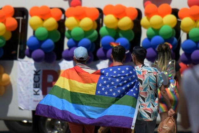 Participants in the LA Pride Parade in West Hollywood cover themselves with the rainbow flag of the gay rights movement