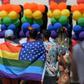 Participants in the LA Pride Parade in West Hollywood cover themselves with the rainbow flag of the gay rights movement
