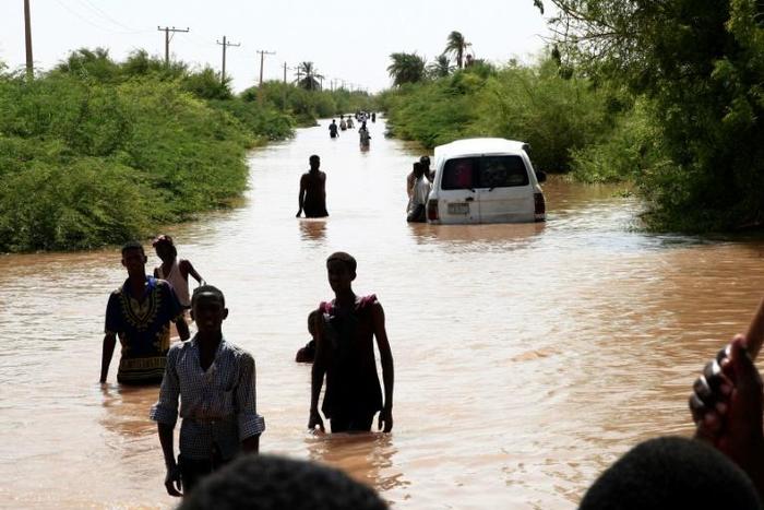 Sudanese people walk a flooded road in Wad Ramli village on the eastern banks of the Nile river