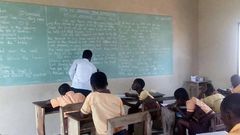 Teachers write exam questions on blackboards