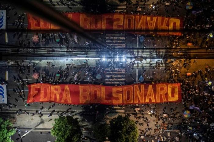 A giant banner reading "Get Out Bolsonaro" is displayed during a strike to protest proposed pension reforms