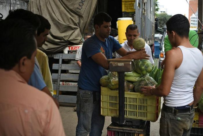 A man sells fruits and vegetables at a street market in Caracas, where a greater choice of products exist, on July 25
